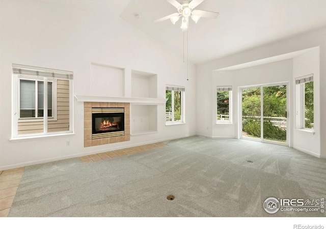 unfurnished living room with light carpet, ceiling fan, a fireplace, and high vaulted ceiling