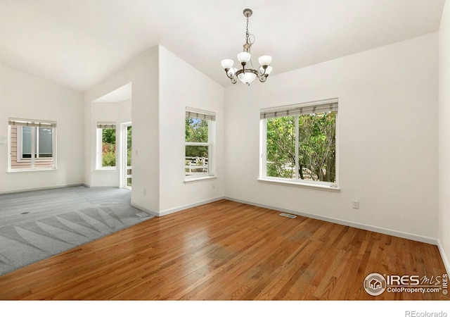 empty room featuring lofted ceiling, an inviting chandelier, and hardwood / wood-style flooring