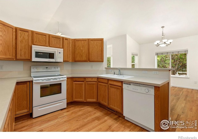 kitchen featuring pendant lighting, white appliances, sink, kitchen peninsula, and light wood-type flooring