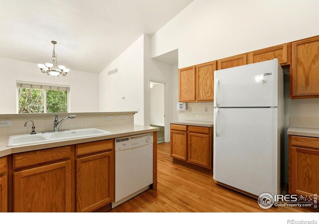 kitchen with decorative light fixtures, light hardwood / wood-style floors, sink, an inviting chandelier, and white appliances