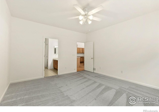 unfurnished bedroom featuring ceiling fan, light colored carpet, and connected bathroom