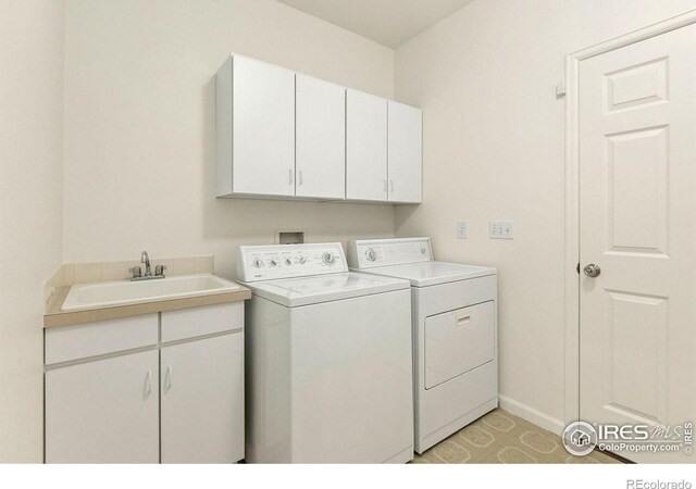 laundry area featuring sink, separate washer and dryer, and cabinets