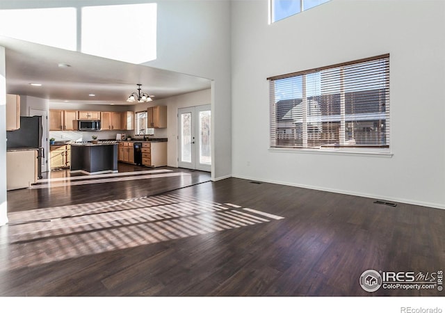 unfurnished living room with hardwood / wood-style flooring, an inviting chandelier, french doors, and a healthy amount of sunlight