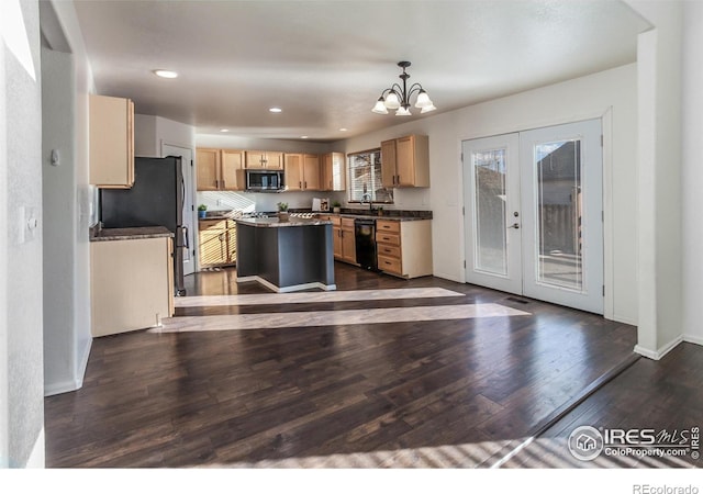 kitchen with appliances with stainless steel finishes, light brown cabinets, a kitchen island, and decorative light fixtures