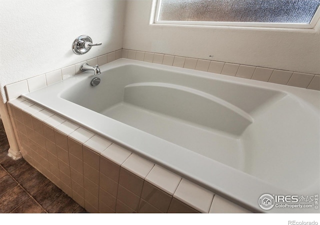 bathroom with tiled bath and tile patterned flooring