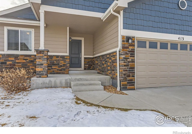 snow covered property entrance featuring a garage