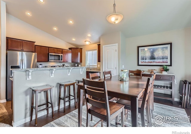 dining room featuring lofted ceiling, sink, and dark wood-type flooring