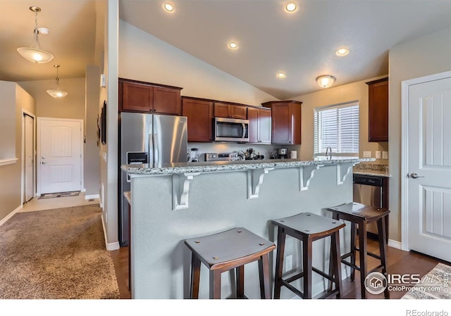 kitchen with light stone counters, a kitchen bar, decorative light fixtures, and appliances with stainless steel finishes