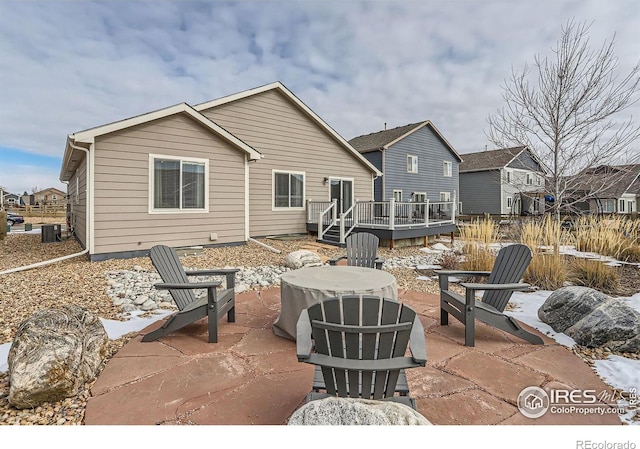 snow covered patio with central AC and a deck