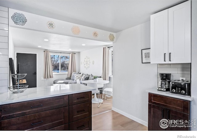 kitchen with light hardwood / wood-style floors, light stone counters, white cabinets, and dark brown cabinets