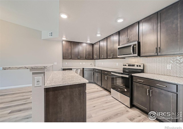 kitchen featuring light wood-type flooring, appliances with stainless steel finishes, light stone counters, and dark brown cabinetry