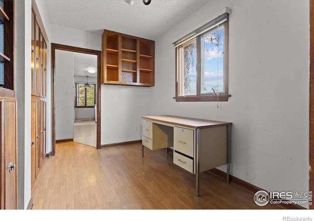 unfurnished office with light hardwood / wood-style floors and a textured ceiling