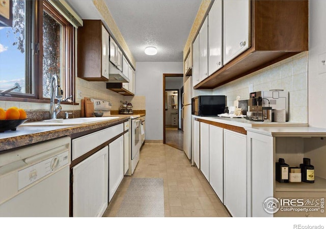 kitchen featuring sink, white appliances, and white cabinetry