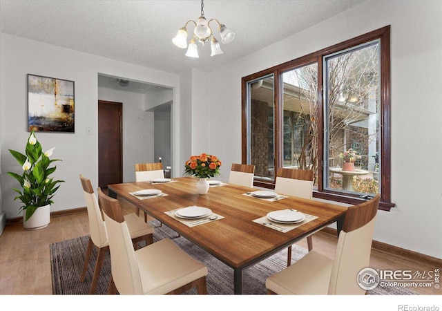 dining room with wood-type flooring, a textured ceiling, and a notable chandelier