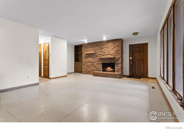 unfurnished living room with built in shelves, a textured ceiling, and a stone fireplace