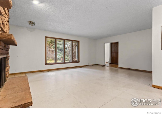 unfurnished living room with a textured ceiling and a stone fireplace