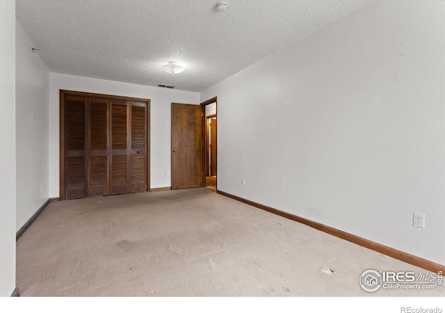 unfurnished bedroom with a textured ceiling, a closet, and light carpet