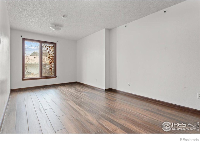 spare room featuring a textured ceiling and dark hardwood / wood-style floors