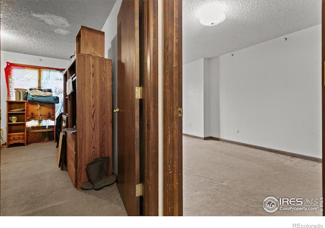 corridor featuring a textured ceiling and light colored carpet