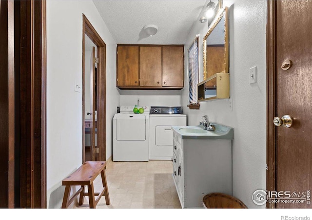 laundry area with cabinets, a textured ceiling, sink, and washing machine and clothes dryer