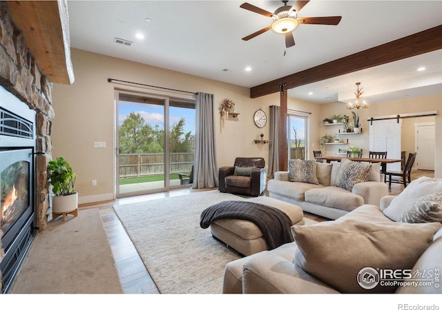 living room with a barn door, light wood-type flooring, beamed ceiling, and a healthy amount of sunlight