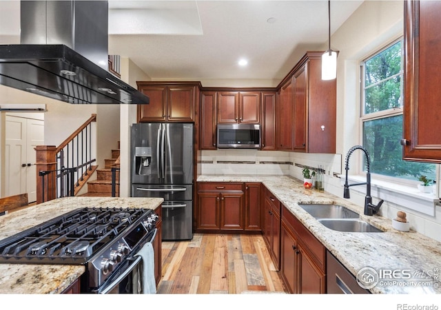 kitchen with pendant lighting, sink, stainless steel appliances, island range hood, and light wood-type flooring