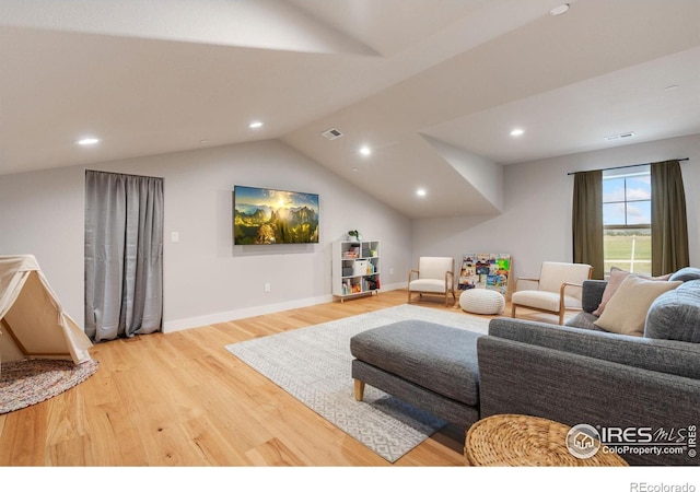 living room featuring lofted ceiling and light hardwood / wood-style floors