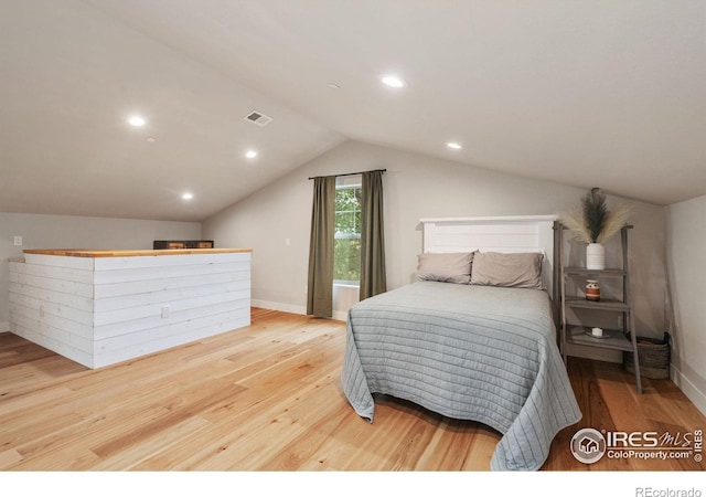 bedroom with vaulted ceiling and light wood-type flooring