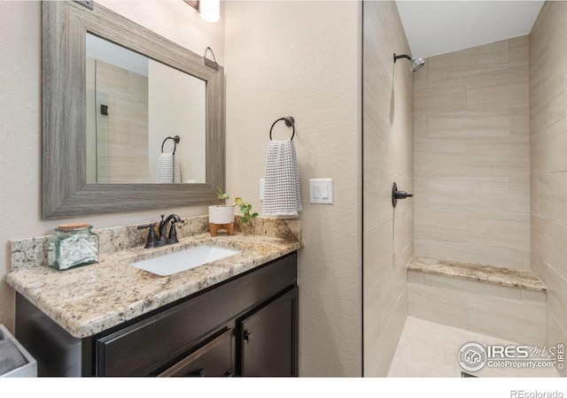 bathroom with vanity and a tile shower