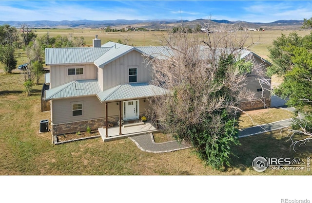 view of front of property with a mountain view, central AC unit, a front lawn, and covered porch