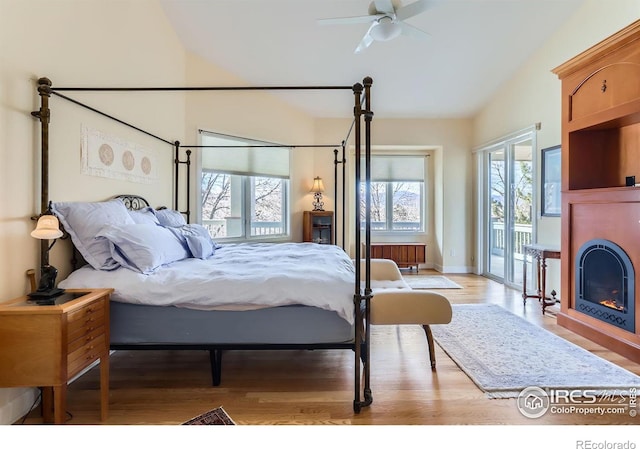 bedroom with radiator, lofted ceiling, access to outside, ceiling fan, and light hardwood / wood-style flooring