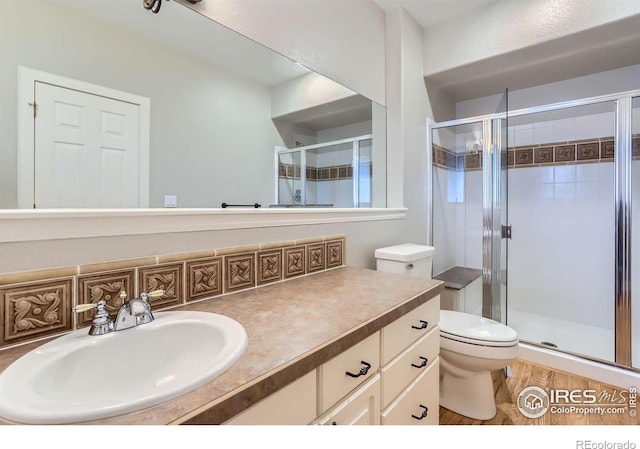 bathroom featuring toilet, vanity, and a shower with shower door