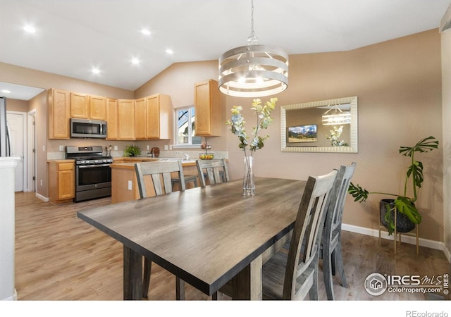 dining room with vaulted ceiling, light hardwood / wood-style flooring, and an inviting chandelier