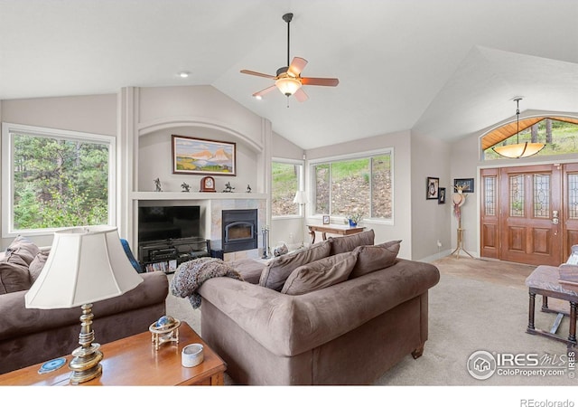 living room with vaulted ceiling, ceiling fan, a wood stove, and plenty of natural light