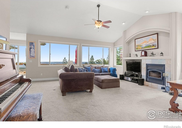 carpeted living room with ceiling fan, vaulted ceiling, and a tiled fireplace