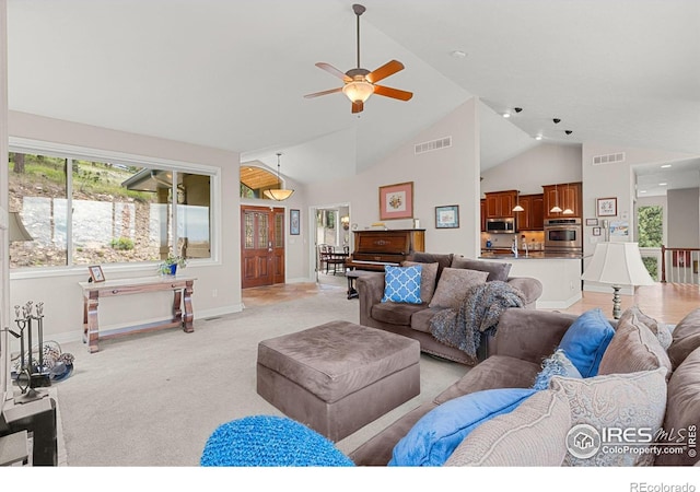 carpeted living room with ceiling fan and vaulted ceiling