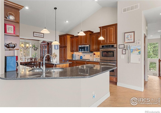 kitchen with vaulted ceiling, a notable chandelier, pendant lighting, sink, and appliances with stainless steel finishes