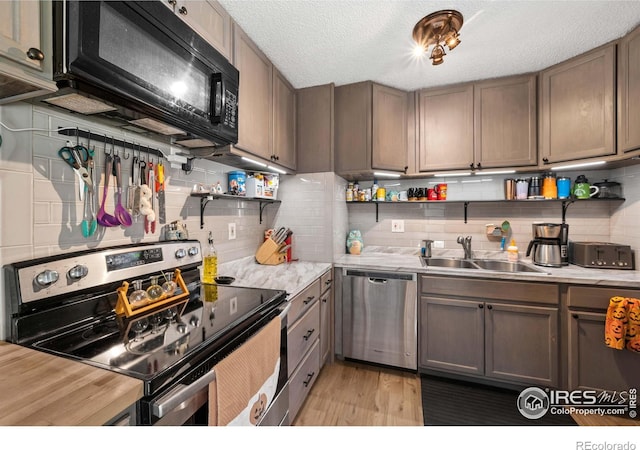 kitchen with appliances with stainless steel finishes, light hardwood / wood-style floors, sink, and decorative backsplash