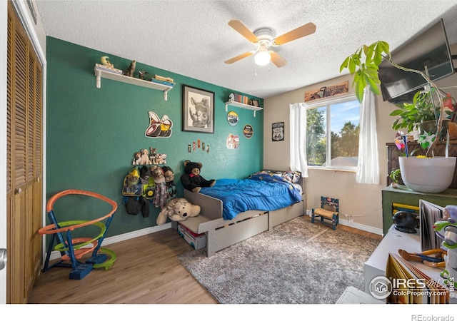 bedroom with ceiling fan, hardwood / wood-style floors, a textured ceiling, and a closet