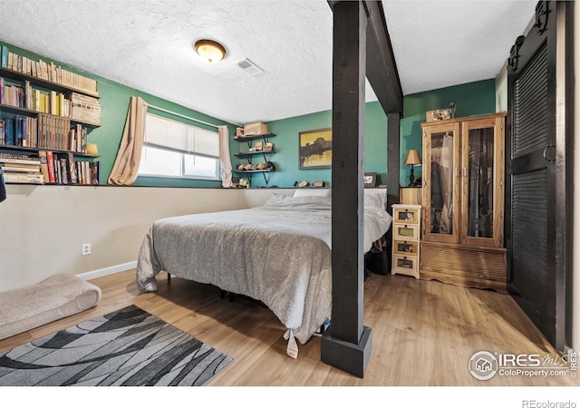 bedroom featuring hardwood / wood-style flooring, a barn door, and a textured ceiling