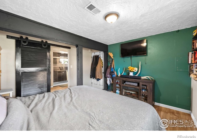 bedroom with hardwood / wood-style floors, a textured ceiling, and a closet