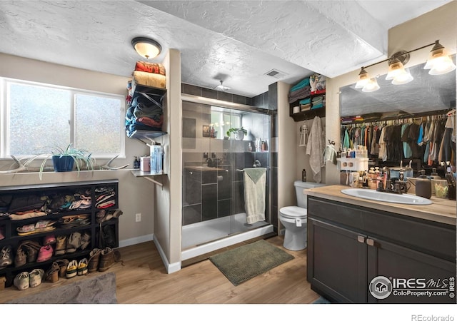 bathroom featuring hardwood / wood-style floors, vanity, toilet, a shower with door, and a textured ceiling