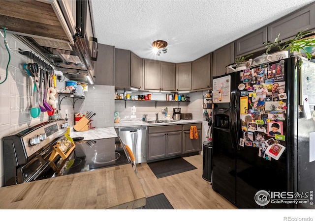 kitchen featuring stainless steel appliances, sink, a textured ceiling, and light wood-type flooring