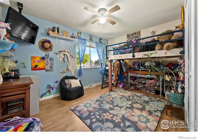 bedroom featuring ceiling fan, wood-type flooring, and a textured ceiling