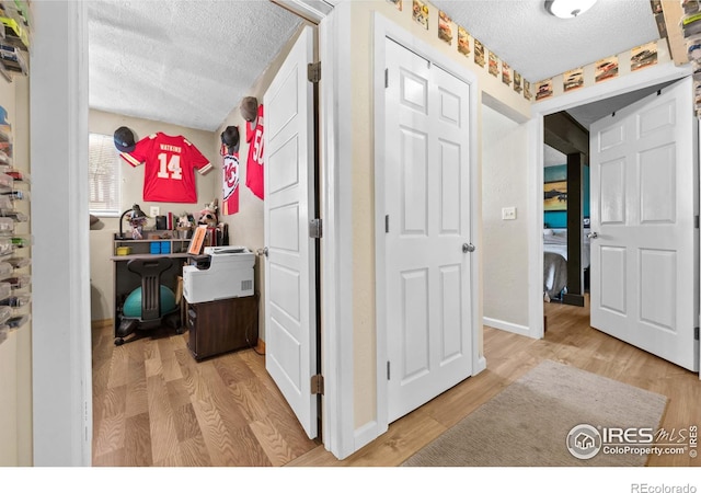 hall featuring light hardwood / wood-style flooring and a textured ceiling