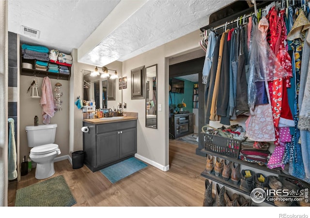 bathroom featuring vanity, hardwood / wood-style floors, a textured ceiling, and toilet