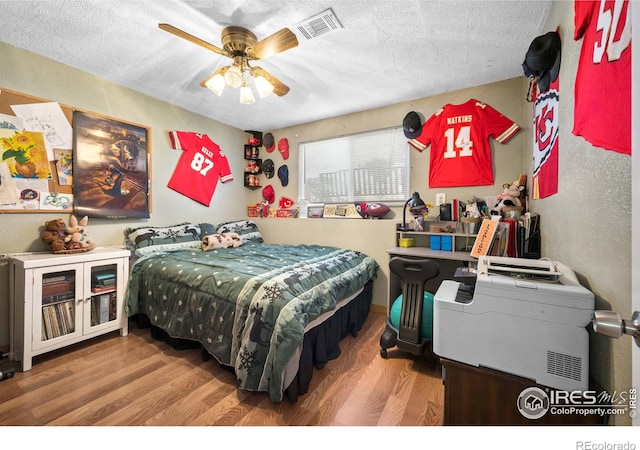 bedroom featuring hardwood / wood-style flooring, ceiling fan, and a textured ceiling