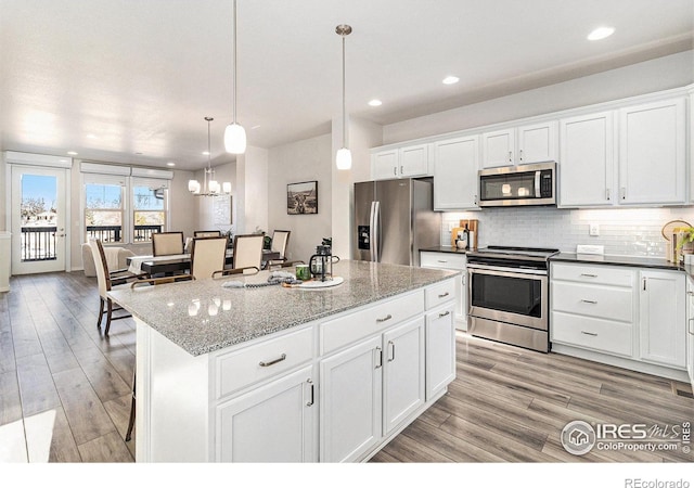 kitchen with decorative light fixtures, white cabinets, appliances with stainless steel finishes, and a center island