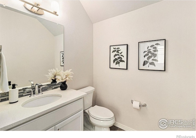 bathroom with toilet, lofted ceiling, and vanity