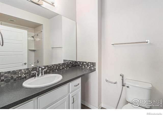 bathroom featuring backsplash, toilet, vanity, and walk in shower